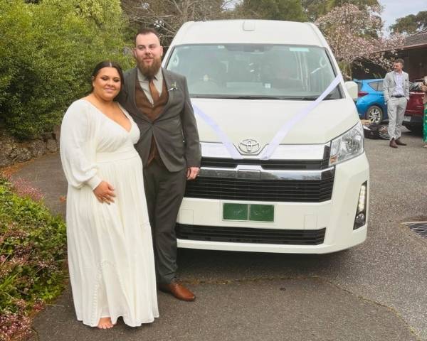 Bride and groom standing in front of decorated maxi cab in Melbourne